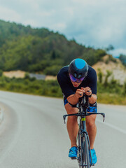 Full length portrait of an active triathlete in sportswear and with a protective helmet riding a...