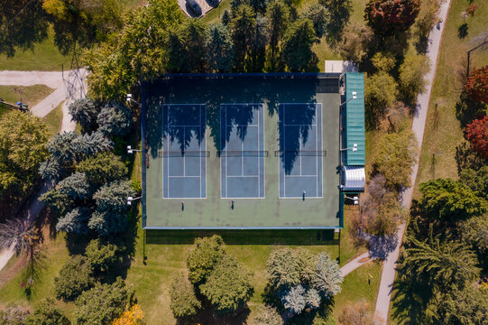 Aerial top down view of community public tennis court. Rising up above tennis stadium. Sunny summer morning day.
