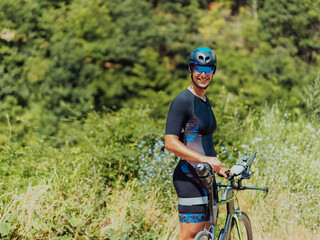Full length portrait of an active triathlete in sportswear and with a protective helmet riding a...