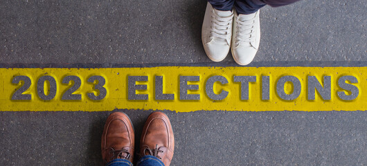 2023 elections illustration. Two people facing each other, divided by a yellow line. Top view, copy space.