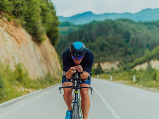 Full length portrait of an active triathlete in sportswear and with a protective helmet riding a bicycle. Selective focus 