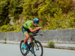 Full length portrait of an active triathlete in sportswear and with a protective helmet riding a bicycle. Selective focus 