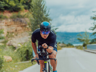 Full length portrait of an active triathlete in sportswear and with a protective helmet riding a bicycle. Selective focus 