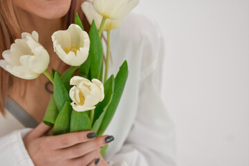 Fototapeta na wymiar Bouquet of white tulips in a female hand on a white background.