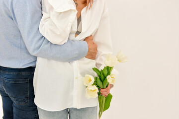 Loving couple holding a bouquet of tulips on a white background.