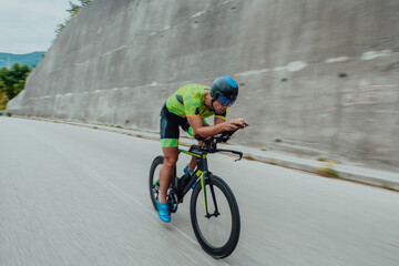 Full length portrait of an active triathlete in sportswear and with a protective helmet riding a...