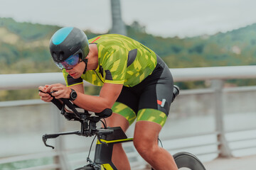 Full length portrait of an active triathlete in sportswear and with a protective helmet riding a...