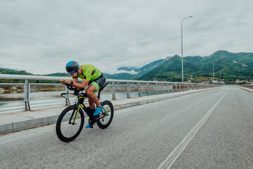 Full length portrait of an active triathlete in sportswear and with a protective helmet riding a...