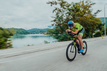 Full length portrait of an active triathlete in sportswear and with a protective helmet riding a...