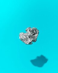 Ball of Crumpled Aluminum Foil Floating Mid-Air on a Blue Background