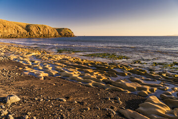 Sunlit beach at Playa de las Coloradas in Playa Blanca, Lanzarote. The beach leads to the headland and cliffs of Papagayo. © Michael Shannon