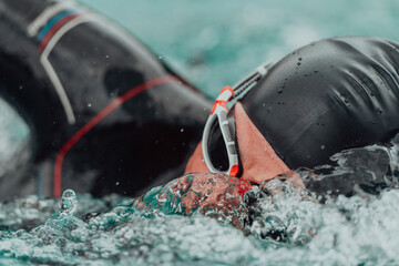 A triathlete in a professional swimming suit trains on the river while preparing for Olympic...