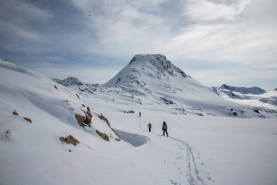 Skiers at the top of a pass with a wide expanse of the Coast Mountains ahead during the Spearhead Traverse in Whistler, British Columbia, Canada.