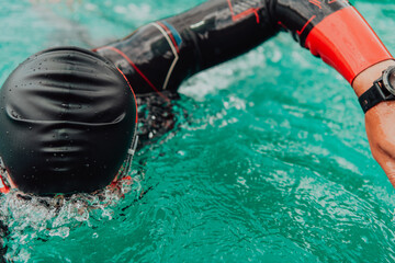 A triathlete in a professional swimming suit trains on the river while preparing for Olympic...