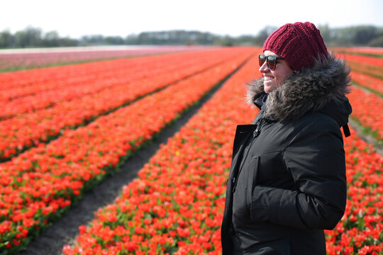 Young woman standing in tulip field smiling in the spring time.