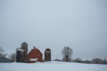 red barn in winter with bare trees and snowy landscape