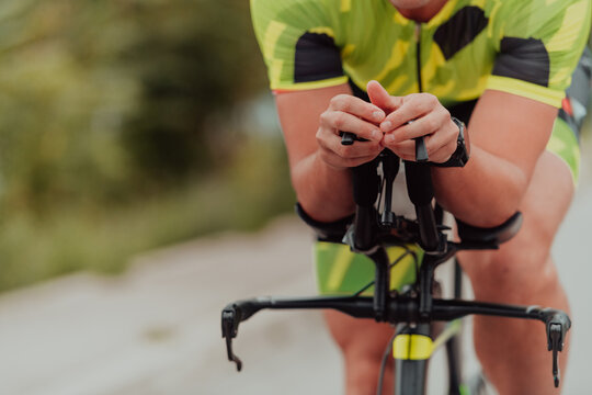 Close up photo of an active triathlete in sportswear and with a protective helmet riding a bicycle. Selective focus