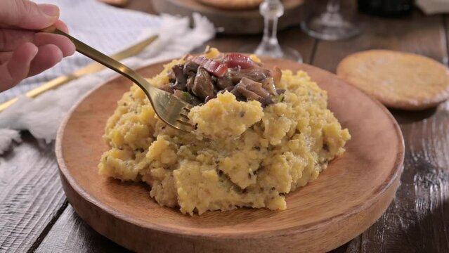 polenta with porcini mushrooms, bacon, served on a dark wooden background. Typical food of northern Italy, Trentino in the Alps . 4k