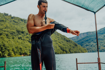 Athlete putting on a swimming suit and preparing for triathlon swimming and training in the river...