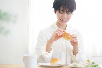 Obraz na płótnie Canvas メインビジュアルにも！パンを食べる女性 朝日が美しい爽やかな朝食の風景