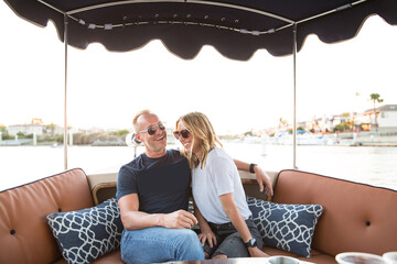 couple sitting on a bench in a duffy boat smiling wearing sunglasses on the water