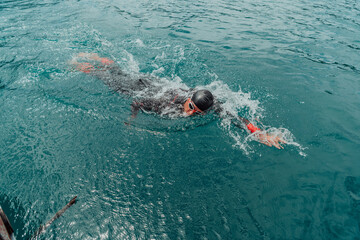 A triathlete in a professional swimming suit trains on the river while preparing for Olympic...