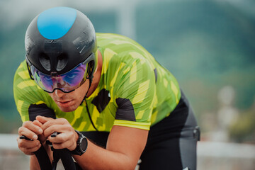 Close up photo of an active triathlete in sportswear and with a protective helmet riding a bicycle. Selective focus - obrazy, fototapety, plakaty