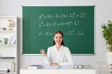 Young math’s teacher giving lesson at table in classroom