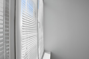 Stylish window with horizontal blinds in room