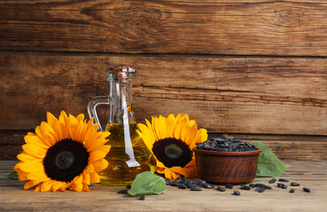 Sunflower cooking oil, seeds and yellow flowers on wooden table