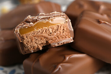 Delicious chocolate candy bars with caramel as background, closeup