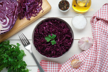 Tasty red cabbage sauerkraut with parsley and different ingredients on white wooden table, flat lay