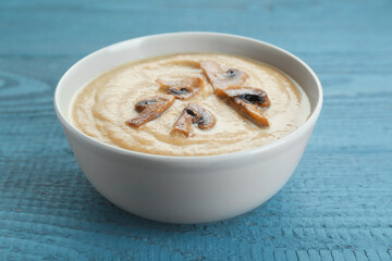 Delicious mushroom cream soup on light grey wooden table, closeup
