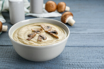 Delicious mushroom cream soup on light grey wooden table. Space for text