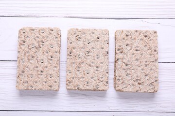 Tasty crispbreads on white wooden table, flat lay