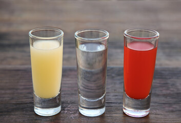 Shots with lime juice, tequila and sangria as colors of mexican flag on wooden table, closeup. Traditional serving