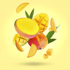 Delicious mango fruits and leaves falling on pale yellow background