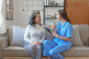 Portrait of attractive young caucasian female nurse elderly caregivers with senior patient home caring for elderly asia female patients on couch, indoors.