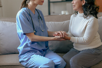 Obraz premium Portrait of attractive young caucasian female nurse elderly caregivers with senior patient home caring for elderly asia female patients on couch, indoors. hand clasp to encourage