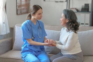Obraz premium Portrait of attractive young caucasian female nurse elderly caregivers with senior patient home caring for elderly asia female patients on couch, indoors. hand clasp to encourage
