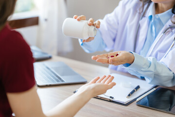 Female elder doctor takes a history of a patient and gives a consultation about osteopathy to a female patient after measuring blood pressure and heart rate and encouragement by holding hands