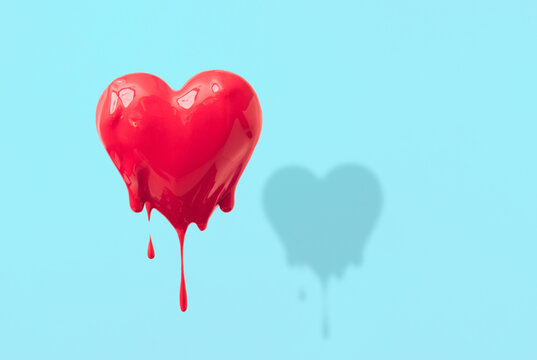 A love composition made of a red heart melting on a blue pastel background. .Minimal concept of Valentine's Day or love. Creative art, minimal aesthetics.