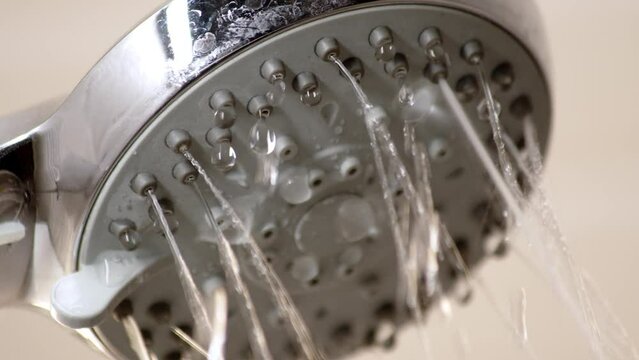 Water is coming from old shower head. Dirty clogged shower head, water channels through which water barely passes. close up view of dripping drops and jets of water in tub.