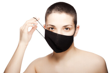 Cute girl with very short hair wearing black protective face mask. Studio portrait isolated on white background..