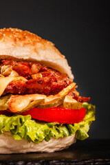 Burger with bacon onions tomatoes cucumber lettuce and souces. Abstract fast food photo.