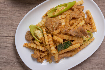 Stir-fried pork with red curry paste and young coconut shoots in a white plate
