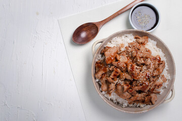 Roast pork with teriyaki sauce sprinkled with white sesame seeds on a white background.