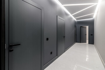 Simple clean newly built generic modern new real estate block of flats interior, long black corridor with black doors, perspective. New bought apartment, new home, hallway abstract concept, copy space - Powered by Adobe