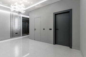 A simple modern gray wall with a black and gray door in an empty room. Interior design element of modern interior design in a modern house