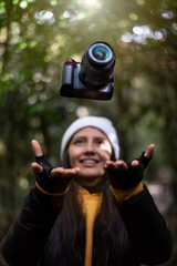 Latin woman throwing a camera in nature vertical